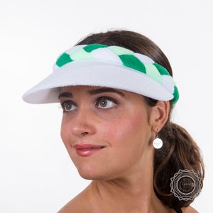 May include: White visor with a green and white braided headband. The headband is made of a soft, stretchy material.