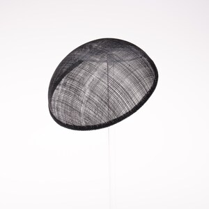 May include: A black fascinator hat with a rounded, dome-shaped silhouette. The headpiece is crafted from a fine, woven mesh material that features a visible grid-like texture throughout the surface, creating a semi-sheer appearance.