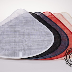 May include: A stack of six hat bases in various colors, including white, black, navy blue, red, and pink. The bases are made of a woven material and have a rounded, slightly pointed shape.