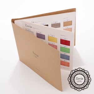 May include: A brown fabric sample book with the word "Zoria" printed on the cover. The book is open to reveal a variety of fabric swatches in different colors and textures.