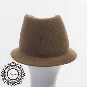 May include: A brown felt fedora hat with a wide brim. The hat is sitting on a white mannequin head.