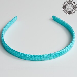 Pu&ograve; includere: Una fascia per capelli turchese con una trama intrecciata. L'accessorio per capelli &egrave; una semplice fascia curva, progettata per essere indossata sulla fronte. La fascia &egrave; di un colore pieno e brillante ed &egrave; probabilmente realizzata in tessuto o materiale simile.