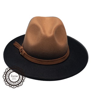 May include: A brown and black fedora hat with a brown leather band and a small tassel. The hat has a wide brim and a slightly rounded crown.