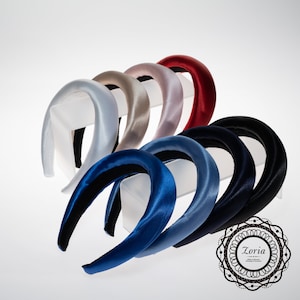 May include: A set of ten satin headbands in various colors, including blue, red, and beige. The headbands are arranged in a semi-circle on a white background.