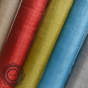 May include: Five rolls of fabric in different colors: beige, red, yellow, blue, and gray. The fabric has a subtle sheen and a woven texture.