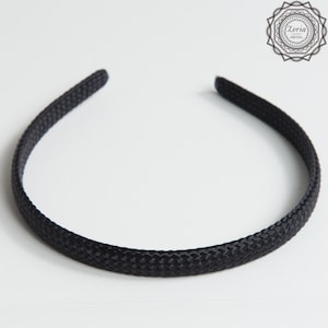 Pu&ograve; includere: Una fascia per capelli nera con una trama intrecciata. Questo accessorio per capelli &egrave; un design semplice ed elegante, ideale per tenere i capelli a posto. La fascia &egrave; di colore nero pieno e viene mostrata su sfondo bianco.