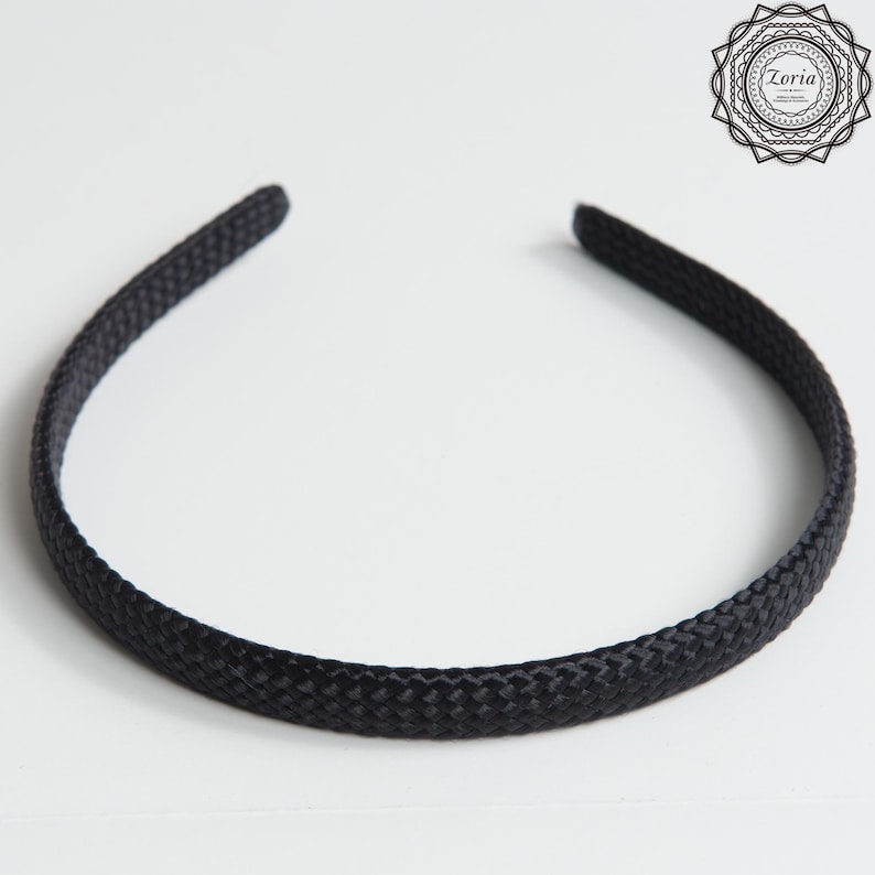 Pu&ograve; includere: Una fascia per capelli nera con una trama intrecciata. Questo accessorio per capelli &egrave; un design semplice ed elegante, ideale per tenere i capelli a posto. La fascia &egrave; di colore nero pieno e viene mostrata su sfondo bianco.