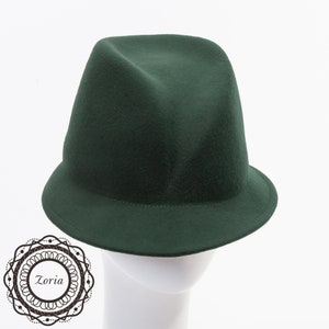 May include: A dark green felt fedora hat with a wide brim. The hat is sitting on a white mannequin head.