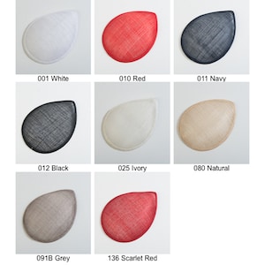 May include: A color card labeled Zoria PSBC-156001 displaying eight teardrop-shaped sinamay fascinator bases in various colors: 001 White, 010 Red, 011 Navy, 012 Black, 025 Ivory, 080 Natural, 091B Grey, and 136 Scarlet Red with visible woven texture.