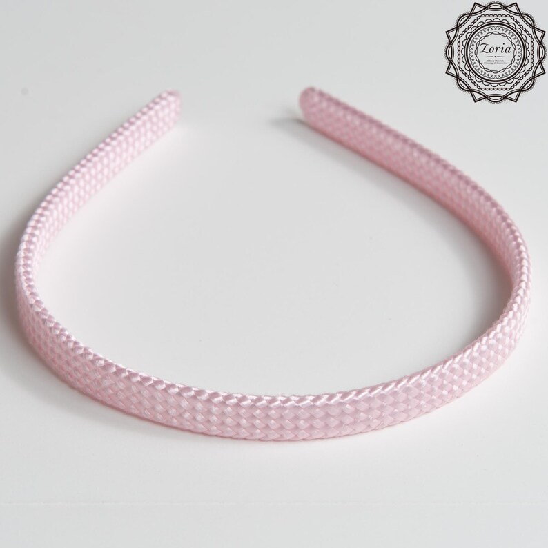 Pu&ograve; includere: Una fascia per capelli rosa chiaro con una trama intrecciata. La fascia ha una forma semplice e curva, progettata per essere indossata sulla testa. La fascia &egrave; realizzata in un materiale morbido e flessibile. Il logo Zoria &egrave; nell'angolo in alto a destra.