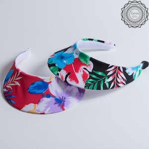 May include: Two floral print visors, one red with white and blue flowers, the other black with white, red, and blue flowers.