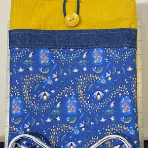 May include: A blue fabric pouch with a yellow top and a denim trim. The pouch has a button closure and a firefly pattern.
