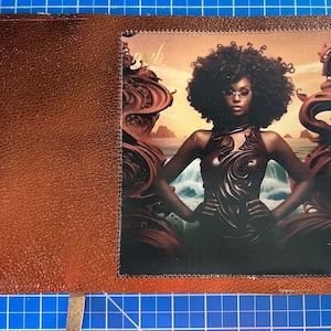 Puede incluir: Una cubierta de diario de cuero marrón con un parche decorativo que presenta a una mujer con cabello rizado que lleva un vestido marrón oscuro y gafas de sol. El parche tiene un borde dorado y la palabra "myth" es visible en la esquina superior izquierda.