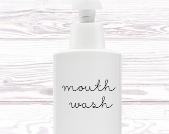 May include: White plastic pump bottle with a black label that says "mouth wash" on a white wood background.