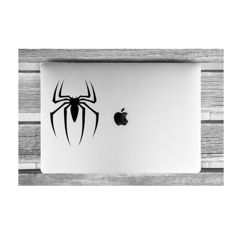 K&ouml;nnte beinhalten: Ein schwarz-wei&szlig;er Spider-Man-Logo-Aufkleber auf einem silbernen Laptop.