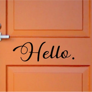 May include: A close-up of a bright orange door with a black vinyl decal that says "Hello."