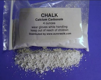 May include: A white powder labeled "CHALK Calcium Carbonate 4 ounces" in a clear plastic bag. The bag is open and the powder is spilling out onto a blue surface. The label also includes the instructions "wear gloves while handling keep out of reach of children" and "Distributed by www.aurorasilk.com".