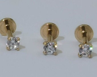 May include: Three gold stud earrings with a single clear gemstone in the center of each earring.