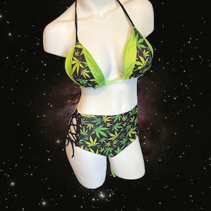 May include: A black and green bikini with a marijuana leaf print. The top is a triangle style with thin straps and the bottom is high-waisted with lace-up sides.