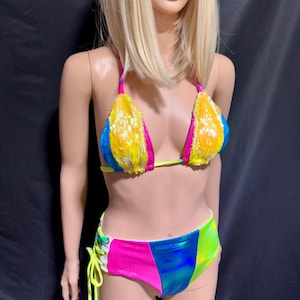 May include: A multi-colored bikini with a sequined top and a high-waisted bottom. The top is blue, pink, yellow, and white. The bottom is pink, blue, and green.
