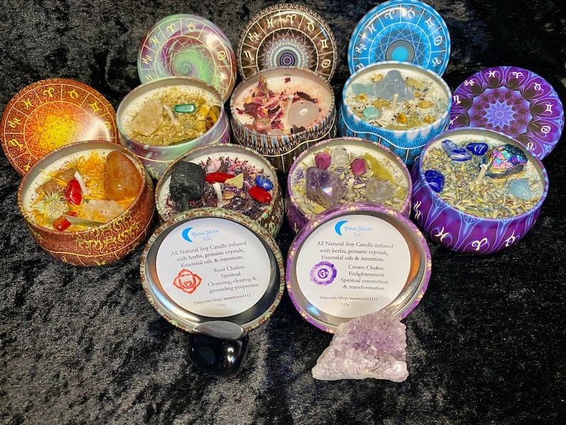 May include: Assortment of seven soy candles in metal tins with lids. Each candle is infused with herbs, gemstones, and essential oils. The candles are decorated with zodiac symbols and chakra symbols. The text on the candle tins reads: "All Natural Soy Candle infused with herbs, gemstone crystals, essential oils & intention. Root Chakra Spiritual Cleansing & grounding properties. Crown Chakra Enlightenment Spiritual connection & transformation."