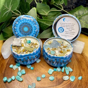 May include: Two blue and white soy candles with a zodiac wheel design. The candles are in small metal tins and are surrounded by green and blue stones. The text on the candle reads "All Natural Soy Candle infused with herbs, genuine crystals, Essential oils & intention. Throat Chakra: Truth Express yourself & speak your truth. Etsy.com/shop/aquamarine111 2 oz"