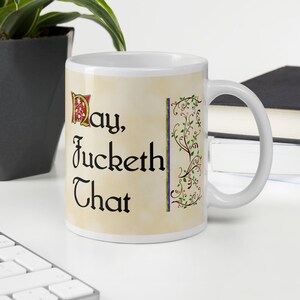 Op de afbeelding: Witte keramische mok met een zwart en gouden ontwerp. De mok heeft een citaat in zwarte letters dat luidt "May, Jucket That".