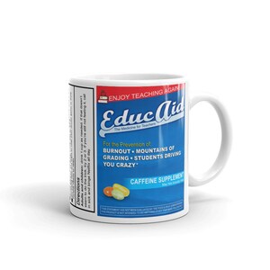 May include: White ceramic mug with a blue and white design. The mug features the text "Educ Aid" and "The Medicine for Teachers". The text "For the Prevention of: Burnout, Mountains of Grading, Students Driving You Crazy" is also on the mug. The mug has a white handle.