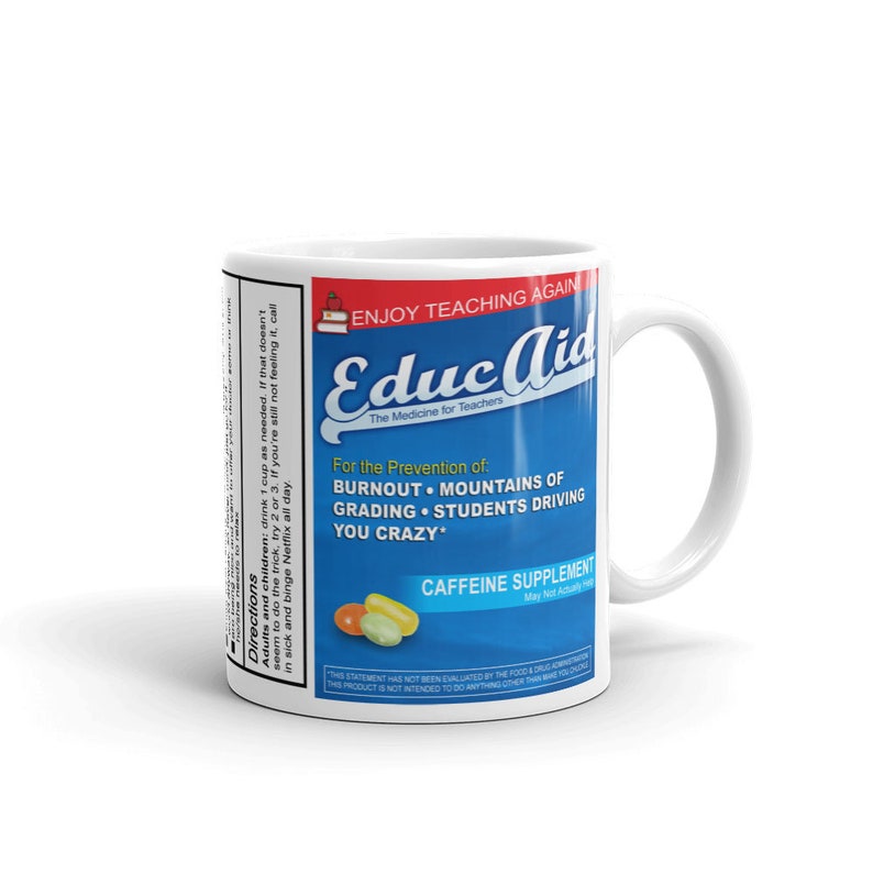 May include: White ceramic mug with a blue and white design. The mug features the text "Educ Aid" and "The Medicine for Teachers". The text "For the Prevention of: Burnout, Mountains of Grading, Students Driving You Crazy" is also on the mug. The mug has a white handle.