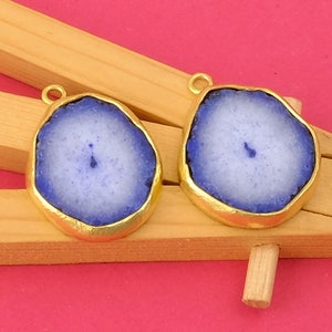 May include: Two gold-plated agate pendant charms with a blue and white color scheme. The agate is a natural stone with a unique pattern.