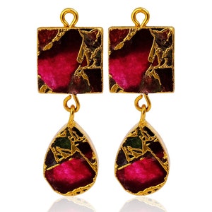 May include: A pair of gold-toned earrings with a square top and a teardrop-shaped bottom. The earrings feature a mosaic of deep pink, green, and brown stones, with gold-colored accents. The earrings are displayed against a white background.