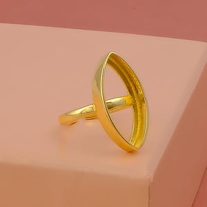 Puede incluir: Un anillo de color dorado con un diseño único de forma ovalada. El anillo es hueco y tiene un acabado liso y pulido.