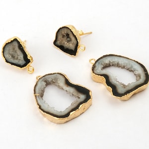 May include: Four gold-plated geode pendants and earrings. The geodes have a black and white centre with a gold-coloured border. Two are earrings with posts, and two are pendants with loops for attaching to jewellery.