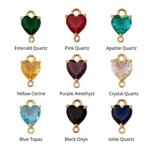 May include: Nine heart-shaped charms with different colored gemstones, including emerald, pink, blue, yellow, purple, clear, black, and blue topaz. Each charm has a gold loop for attaching to jewelry.