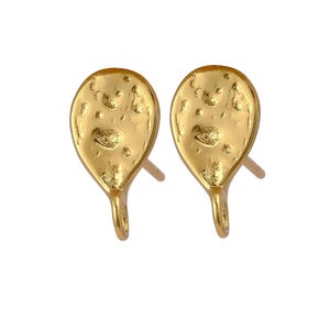 May include: A pair of gold-toned earrings with a textured, hammered, oval-shaped design. The earrings have a post and a small loop at the bottom.