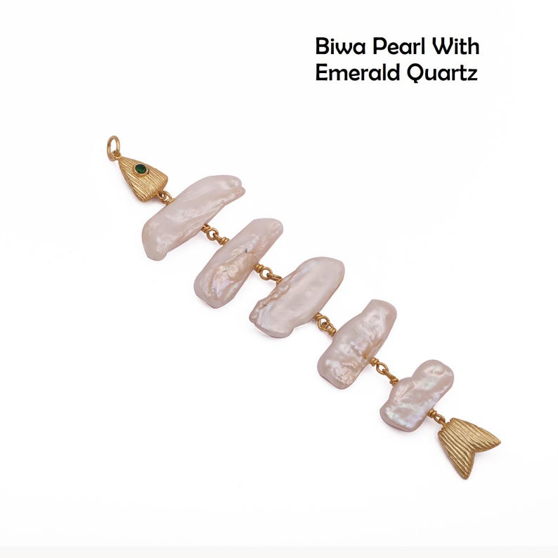 May include: A pendant shaped like a fish, featuring a textured gold-tone head with an inset green emerald quartz, a body composed of five elongated, iridescent white Biwa pearls linked by gold-tone metal, and a textured gold-tone tail fin.