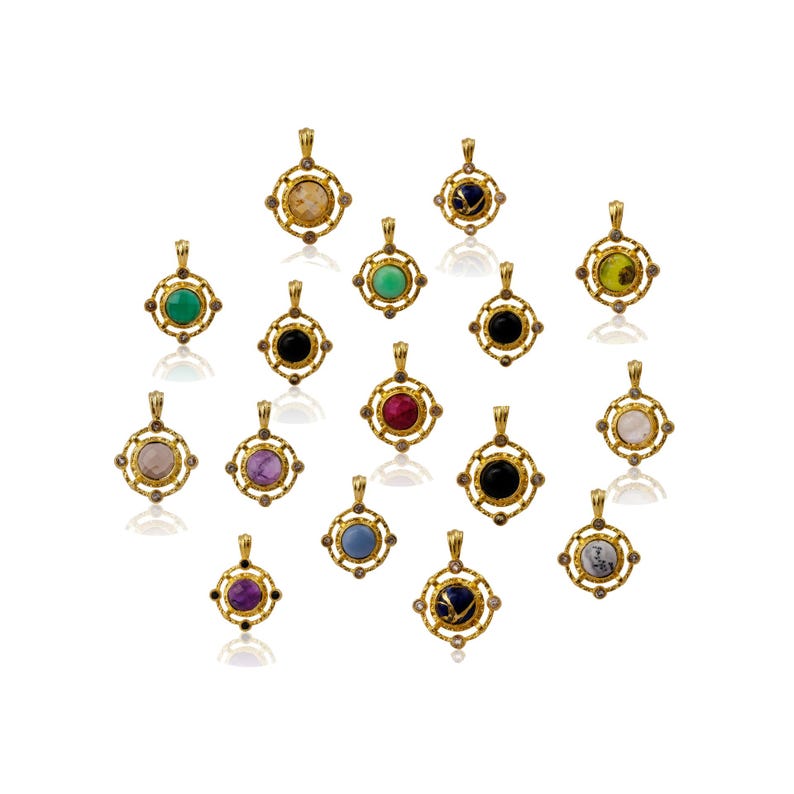 May include: A selection of gold-coloured pendants featuring diverse gemstones. Each pendant has a square frame with a circular gemstone at its centre. The gemstones are in shades of green, red, black, purple, and blue.