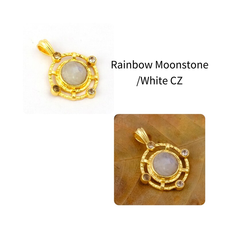 May include: Gold-colored pendant with a central, round, light-colored stone, surrounded by a decorative gold frame. The pendant has a loop at the top for a chain. The text "Rainbow Moonstone / White CZ" is visible.