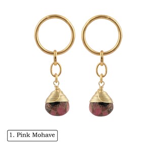 Op de afbeelding: Een paar gouden creolen met roze en zwarte edelsteen druppels. De oorbellen hebben een eenvoudig ontwerp en zijn perfect voor dagelijks gebruik.