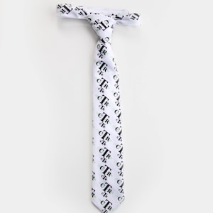 May include: White necktie with a repeating pattern of the letters "cTr" in black and light green. The tie is knotted at the top and hangs vertically against a white background. The tie's design is visible from top to bottom.