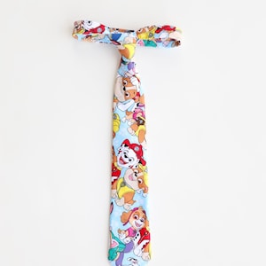 May include: A blue and white tie with a pattern of cartoon dogs from the show Paw Patrol. The dogs are wearing their signature uniforms and are in various poses.