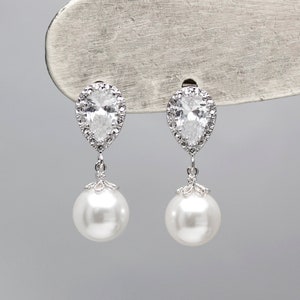 May include: A pair of silver teardrop earrings with a pearl drop and a clear crystal halo.