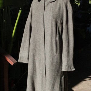 May include: A gray wool coat with a classic design. The coat features a notched collar, a single-button closure, and a tailored fit. It has long sleeves with cuffs and a front pocket. The coat is displayed on a mannequin.