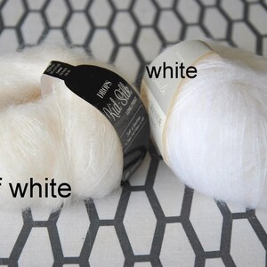 May include: Two skeins of Drops Kid-Silk yarn, one off-white and one white, are displayed against a geometric patterned background. The off-white skein has a black label. The word "white" is written on the white skein.