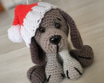 May include: A crocheted gray and brown dog wearing a red and white crocheted Santa hat.