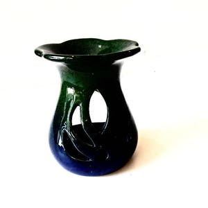 May include: A green and blue ceramic oil burner with a decorative cutout design. The burner has a wide, flat top and a rounded base.