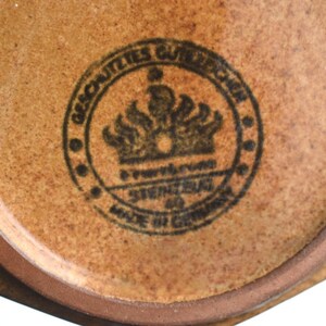 Może przedstawiać: Zbliżenie na brązowy ceramiczny garnek z czarną pieczęcią, na kt&oacute;rej widnieje napis "Geschuetztes Warenzeichen" i "Steingut Made in Germany".