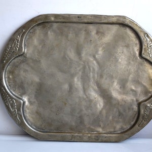 Puede incluir: Una bandeja ovalada de servir de plata con un diseño floral decorativo alrededor del borde.