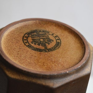 Może przedstawiać: Brązowy, ośmiokątny wazon ceramiczny z czarną pieczątką na spodzie, na kt&oacute;rej widnieje napis "Made in England, Denby Pottery, Made in England".