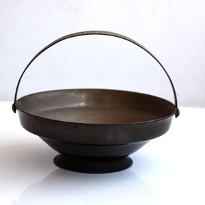 May include: A black metal bowl with a handle. The bowl has a flared rim and a round base.